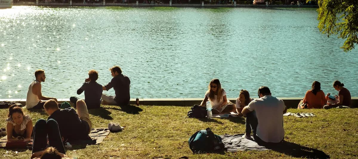 Menschen sitzen auf einer Wiese am Fluss