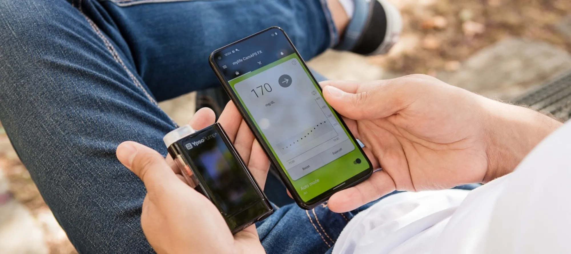 Junger Mensch hält seine mylife YpsoPump und die CamAPS FX App in den Händen