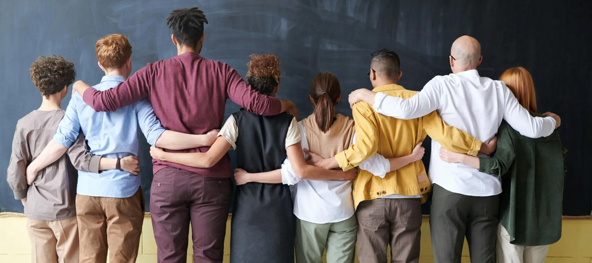 Gruppe von Menschen vor einer Tafel mit dem Rücken zum Betrachter