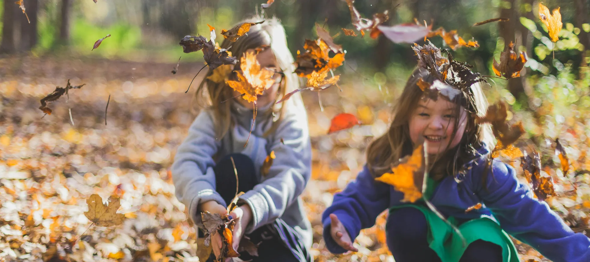 Kinder spielen mit Laub im Herbst