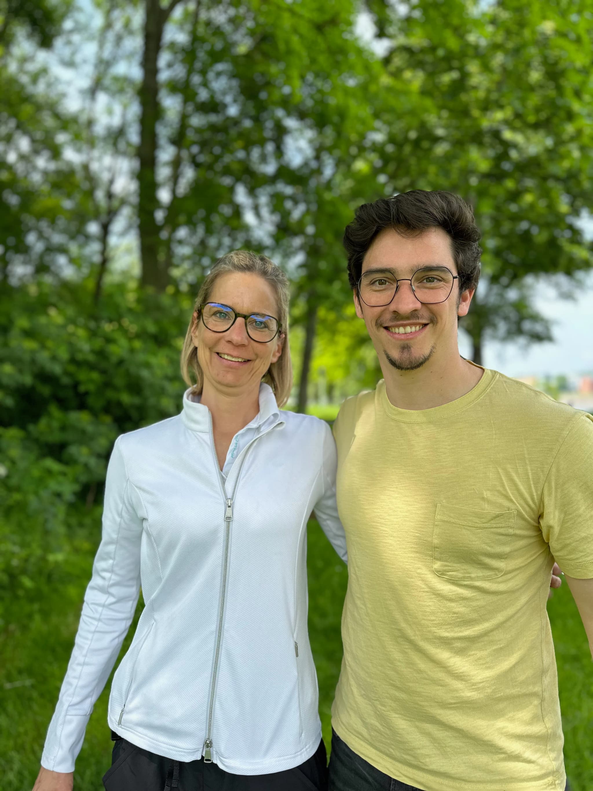 Mann und Frau nebeneinander auf einer Wiese vor Bäumen